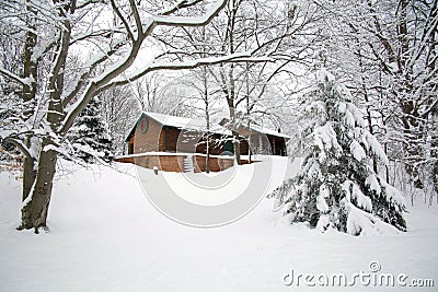 Log home nestled in a snow covered woods Stock Photo