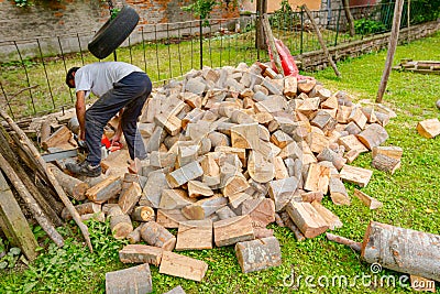 Logger is cutting firewood in the yard with chainsaw Stock Photo