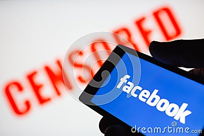 Logo of the Facebook. Red censored text blurred on background. The concept of censorship on popular social networks. Shallow DOF Editorial Stock Photo