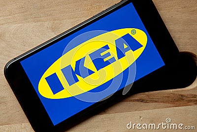 Logo of Ikea on iPhone 11 screen on a wooden bench. Editorial Stock Photo