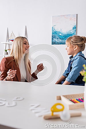 Logopedist talking with smiling girl near Stock Photo