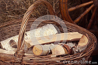 Logs lie in a wicker basket with a handle on the background of haystacks Stock Photo