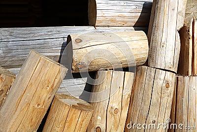 Logs from which to build a frame. Pieces of logs near the wall of a wooden house. Stock Photo