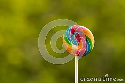 Lollipop, Big Round Rainbow colored lollipop isolated grass Green background Stock Photo