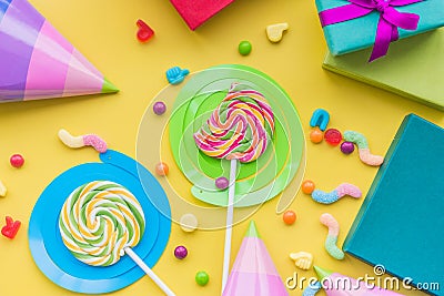 Lollipops and party hats for happy birthday on yellow background top view Stock Photo