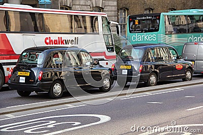 London black taxi following each other in front of the busses on the road Editorial Stock Photo