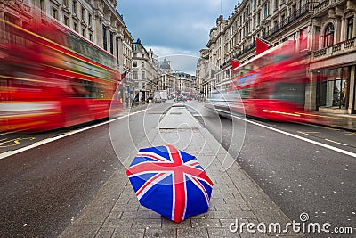 London, England - British umbrella at busy Regent Street with iconic red double-decker buses Stock Photo