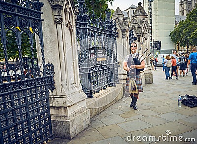 LONDON England - 08/21/2019: scottish bagpiper knocking on the door of the English parliament Editorial Stock Photo