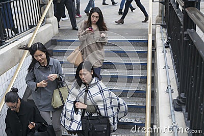 Three fashionably dressed girls in ponchos and raincoats descend the subway stairs near Oxford Street Editorial Stock Photo