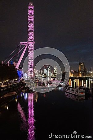 London eye at night being lit by purple lights. Parliament house can be seen in the distance Editorial Stock Photo