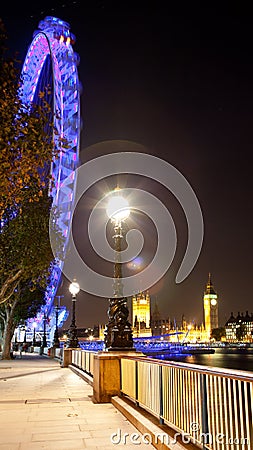 Portrait view of Houses of Parliament, Big Ben and the London Eye at night from the South Bank Editorial Stock Photo