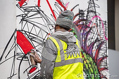 London, January 26, 2020. Professional painter at work, painting a street wall.Young man painting the wall, street art in process Editorial Stock Photo