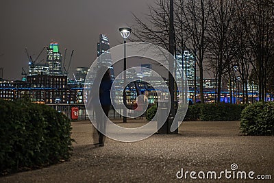 London skyline with an unrecognizable woman walking at night Stock Photo