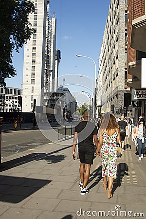 London, U.K., August 22, 2019 - cheerful young afro american couple walking on urban street in london. Editorial Stock Photo