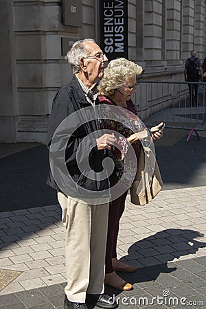 London, U.K. August 22, 2019 - Mature, senior attractive couple on vacation looking at a map on London street Editorial Stock Photo