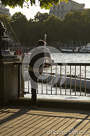 London, U.K. August 22, 2019 - Young man from the back, businessman standing at the Thames riverside in the city of London Editorial Stock Photo