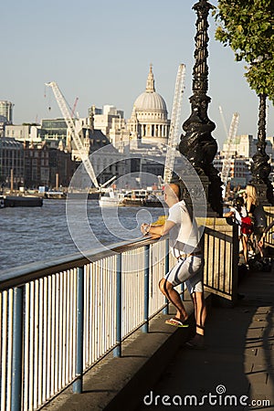 London, U.K. August 22, 2019 - Young man from the back, businessman standing at the Thames riverside in the city of London Editorial Stock Photo