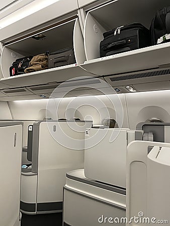 Overhead lockers, luggage and seating in Business Class on a modern jet. Editorial Stock Photo