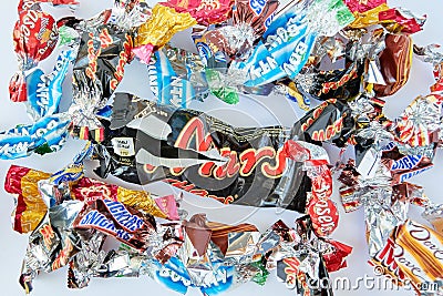 Torn wrappings of a mix of popular candy bars, in mini sizes, with a big Mars candy bar in the middle Editorial Stock Photo