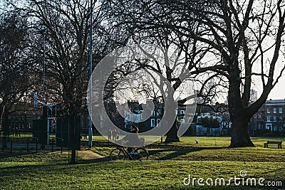 Woman cycling in Haggerston Park in Hackney, East London, UK Editorial Stock Photo