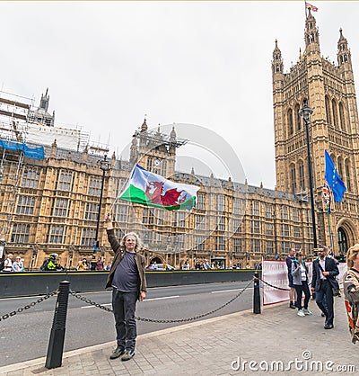 London / UK - June 26th 2019 - Pro-EU protester carries Wales and European Union flags outside Parliament in Westminster Editorial Stock Photo