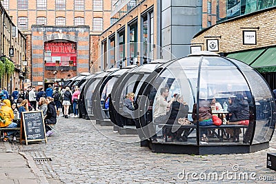 Igloos and winter pop-ups to lunch or dine in Camden lock market. People with meals inside transparent Editorial Stock Photo