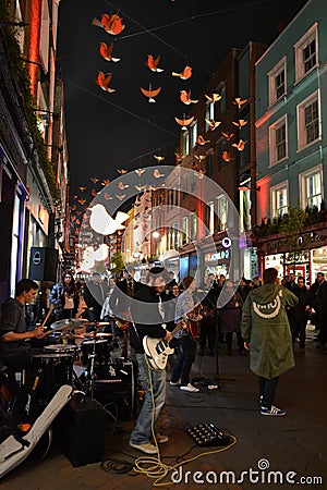 Music band is playing in the London Carnaby street decorated for Christmas holidays and brightly illuminated by night. Editorial Stock Photo