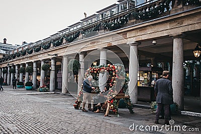 People sitting at a bench decorated with Christmas baubles in Co Editorial Stock Photo