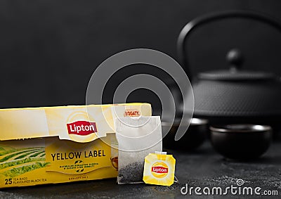 LONDON, UK - OCTOBER 21, 2020: Pack of Lipton Yellow Label black tea with tea bag and iron teapot on black Editorial Stock Photo