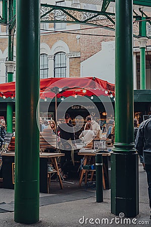 View through the columns of people at a cheese stand inside Borough Market, London, UK. Editorial Stock Photo