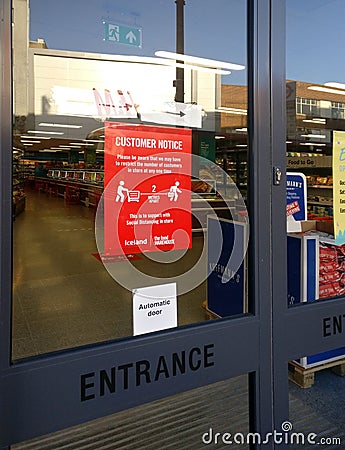 London, United Kingdom - March 31, 2020: Red poster advising customers to practise social distancing while shopping at entrance to Editorial Stock Photo