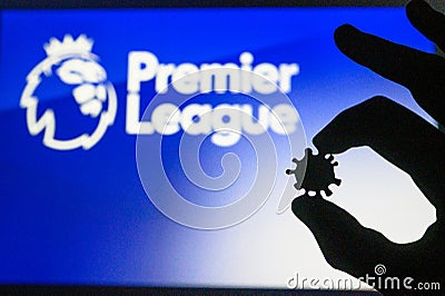 LONDON, UNITED KINGDOM - MAY 25, 2020: Hand silhouette hold covid 19 virus, Premer League tittle in background Editorial Stock Photo