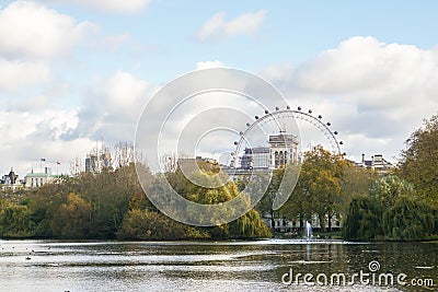 London / United Kingdom - November 10 2019: peaceful lake with trees changing color in autumn in St. James Park with ferris wheel Editorial Stock Photo