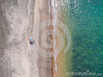 A lone beach umbrella on the sand beach, flat aerial view for background Stock Photo