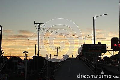 Lone bicycle cyclist riding across a city bridge on a summer day after work riding into the sunset, Melbourne city, Victoria, Stock Photo