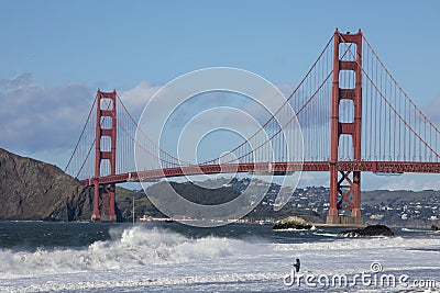 A lone fisherman fishes in the waves next to the famous Golden Gate Bridge in San Francisco Stock Photo