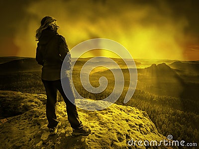 Lone girl with hands in pocket stay at mountain edge. Woman walks Stock Photo