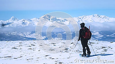 Lone hiker on the snow looking at the horizon and the snow-covered alpine valley Editorial Stock Photo