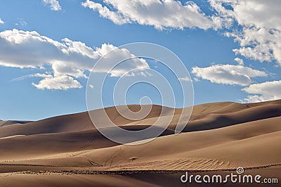 A lone hiker walks the ridge at Great Sand Dunes National Park on a sunny day Stock Photo