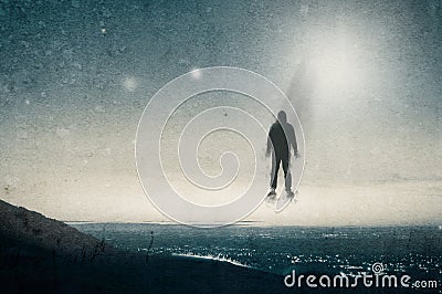 A lone hooded figure floating above a hill looking across a city at night, with UFOs floating in the sky. With a grunge, vintage e Stock Photo