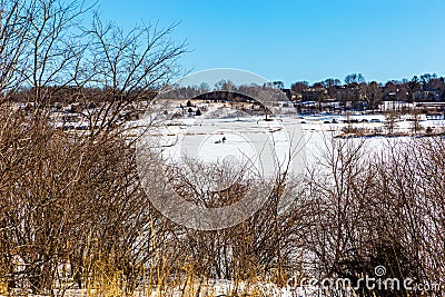 Lone man drilling for ice fishing on frozen lake Stock Photo