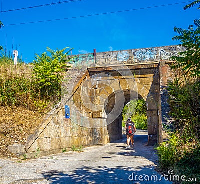 A lone pilgrim passes under a weathered stone arch on the Camino de Santiago Editorial Stock Photo