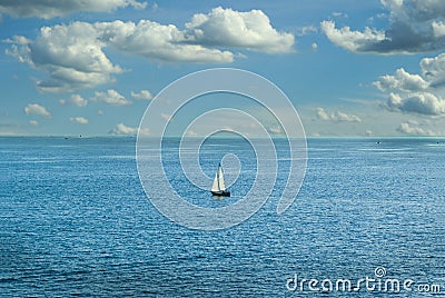 A lone sailboat out in the ocean with a nice breeze and a cloudy but clear sky. Stock Photo