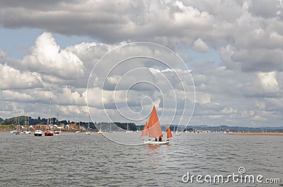 Starcross, devon: sailing boat with dark orange sails, clouds Editorial Stock Photo
