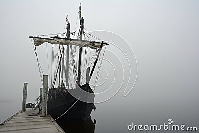 A lone ship is tethered to the dock on a foggy day Stock Photo