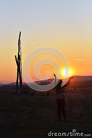 The lone woman raising her arms in awe at the powerful waves on the cliffs edge in county clare ireland in glorious sunset Stock Photo