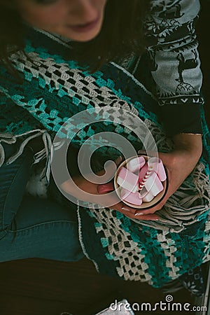 Loneliness christmas - girl sitting alone holding cup with marshmallow in a hands. Stock Photo