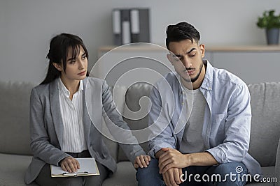 Loneliness, despair and depression concept. Professional psychologist comforting unhappy man, sitting in office Stock Photo