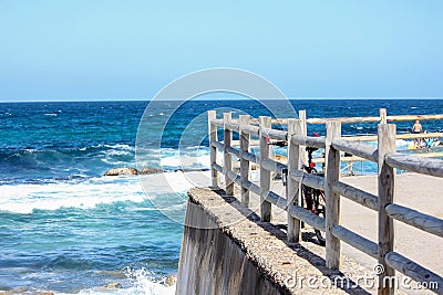 Lonely bicycle on wooden rail on top of rocky walkway at the beach sea waves Stock Photo