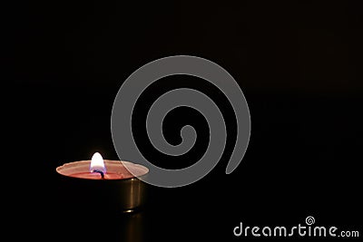 A lonely candle burns in the darkness Stock Photo